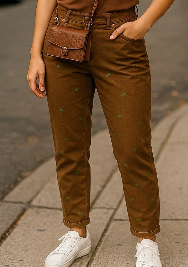 Brown embroidered trousers with small green details, styled with white trainers – preloved women’s trousers.